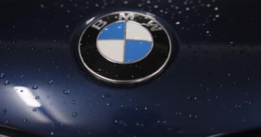 Berlin, Almanya... 10.04.2022 BMW logosu yeni bir arabanın kaputunda. Servis az önce arabayı yıkadı. Logonun etrafında su damlacıkları var. Yüksek kalite 4k görüntü