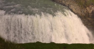 Arka planda gökkuşağı olan doğal bir şelaleden gelen güçlü bir su akıntısı..