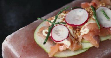 Turp, elma ve kuşkonmazla servis edilen pembe Himalaya tuz bloğunda taze balık sunumu. Haute cuisine konsepti. Yüksek kalite 4k görüntü