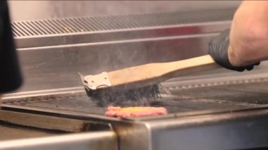 Zararlı tortuyu temizlemek için ızgarayı fırçayla temizlemek ve hamburger servis eden bir kafede yanmış yağ. Amerikan sokak yemeği. Yüksek kalite 4k görüntü