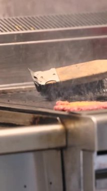 Zararlı tortuyu temizlemek için ızgarayı fırçayla temizlemek ve hamburger servis eden bir kafede yanmış yağ. Amerikan sokak yemeği. Yüksek kalite 4k görüntü