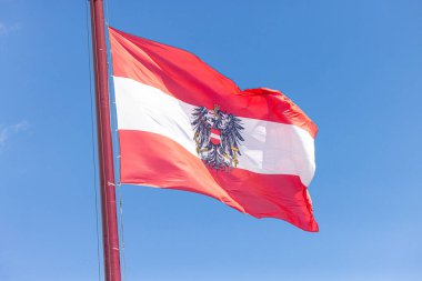 Avusturya Bayrağı 'nın arkaplanda Avusturya Ulusal Günü' nde mavi bulutlu bir gökyüzü olan bir direkte dalgalanması. Yüksek kalite 4k görüntü