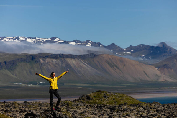 Active people in nature concept. Dressed bright yellow jacket female backpacker enjoying the view as she have mountain walk.Tourist in Iceland. Adventure concept. High quality photo