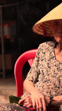 Danang, Vietnam - 30 Haziran 2024 Danang, Vietnam 'da bir sokak pazarında saman şapkalı yaşlı kadın. Yüksek kalite 4k görüntü