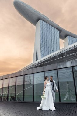 Gelin ve damat, Singapur şehrinin arka planına karşı. Güneşin doğuşu düğün fotoğrafı. - Evet. Yüksek kalite fotoğraf