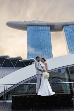 Gelin ve damat, Singapur şehrinin arka planına karşı. Güneşin doğuşu düğün fotoğrafı. - Evet. Yüksek kalite fotoğraf