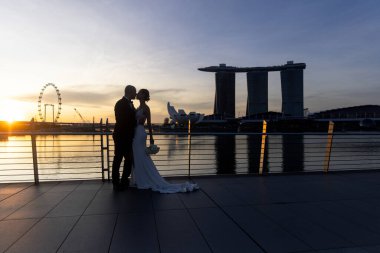 Gelin ve damat, Singapur şehrinin arka planına karşı. Güneşin doğuşu düğün fotoğrafı. - Evet. Yüksek kalite fotoğraf