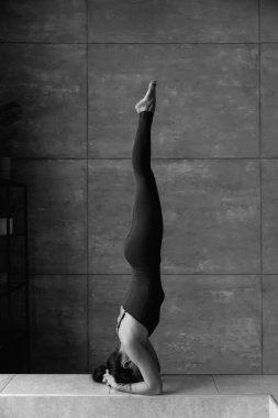 Genç sportif çekici kadın yoga yapıyor, amuda kalkıyor, salamba sirsasana pozu veriyor, yüksek kaliteli fotoğraf çekiyor.