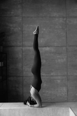 Genç sportif çekici kadın yoga yapıyor, amuda kalkıyor, salamba sirsasana pozu veriyor, yüksek kaliteli fotoğraf çekiyor.