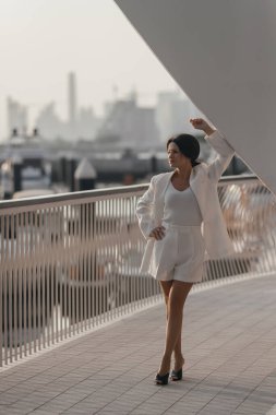 Dubai 'nin arka planına karşı beyaz takım elbiseli bir kadın. Yüksek kalite fotoğraf