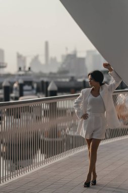 Dubai 'nin arka planına karşı beyaz takım elbiseli bir kadın. Yüksek kalite fotoğraf