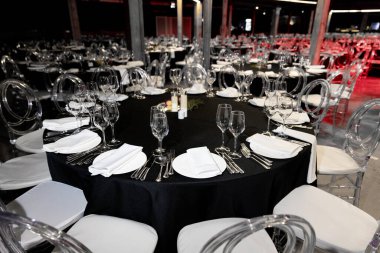 Şölen salonunda zarif bir yuvarlak masa, tabaklar, bardaklar ve yemek tabaklarının yakın çekimi. Yüksek kalite fotoğraf