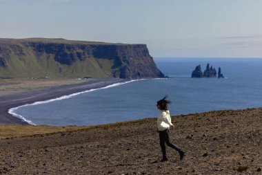 İzlanda 'da Vik plajı manzaralı bir uçurum boyunca koşan bir kız. Yüksek kalite fotoğraf