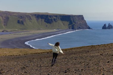 İzlanda 'da Vik plajı manzaralı bir uçurum boyunca koşan bir kız. Yüksek kalite fotoğraf