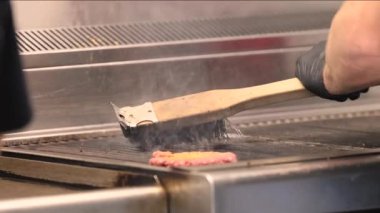 Zararlı tortuyu temizlemek için ızgarayı fırçayla temizlemek ve hamburger servis eden bir kafede yanmış yağ. Amerikan sokak yemeği. Yüksek kalite 4k görüntü
