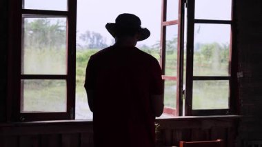 Tanımlanamayan bir erkek yolcunun silueti antik bir ahşap pencerenin arka planına karşı. Yüksek kalite 4k görüntü