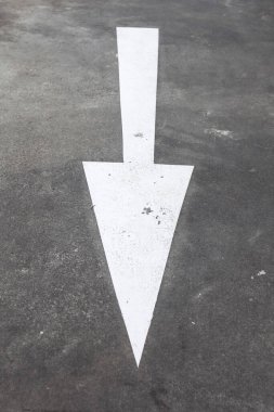 Asfalt bir yolda beyaza boyanmış aşağı bakan büyük bir ok. Şehirdeki yol işaretleri. Yüksek kalite fotoğraf