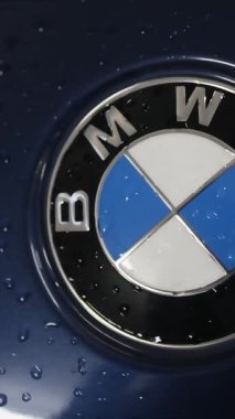Berlin, Almanya... 10.04.2022 BMW logosu yeni bir arabanın kaputunda. Servis az önce arabayı yıkadı. Logonun etrafında su damlacıkları var. Yüksek kalite 4k görüntü