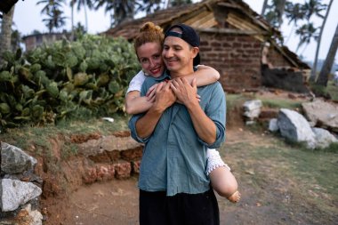 Birbirine aşık bir çift, palmiye ağaçlarının ve sahil evinin zeminine sarılıyor. Konsept doğada plaj tatili ile ilgili. Yüksek kalite fotoğraf