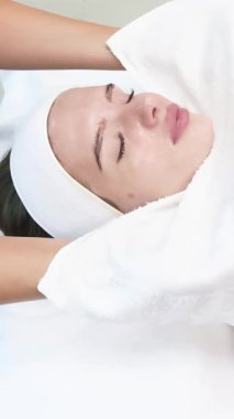 Sıcak, yumuşak bir bez nazikçe tenine dokunur. Yetenekli bir uzman dikkatli bir şekilde pürüzsüz yöntemlerle hassas dokunuşlar yapar. Güzellik, kaplıca, sağlık ve bakım için ideal. Yüksek kalite 4k görüntü