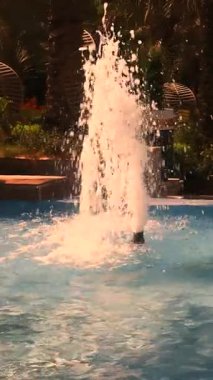 Yazın gök mavisi bir havuzdan bir çeşme patlar. Yüksek kalite 4k görüntü