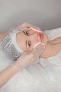 Yumuşak pamuklu mermileri kullanarak nazik bir yüz arındırma. Güzel, açık tenli bir bayan için güzellik merkezinde yapılan bir seansın parçası olarak. Yüksek kalite fotoğraf