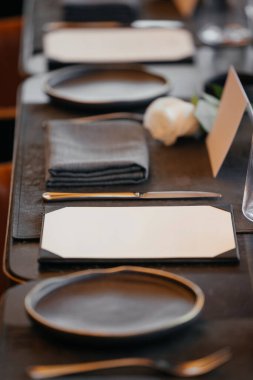 Beyaz menü, peçete ve çatal bıçak takımı lüks bir restoranda karanlık bir masada. Yüksek kalite fotoğraf