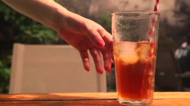 Bir el, buğulanmış soğuk bir bardak limon çayına uzanır. Açık narenciye ve serin nemle sıcak havada susuzluğu gidermek için mükemmel ferahlatıcı bir yaz içeceği. Yüksek kalite 4k görüntü