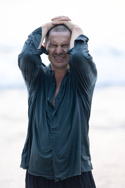 An attractive light-skinned Caucasian man after a hair transplant. Hair is growing after the transplant operation. The man is dressed in red pants and a shirt. Short haircut. The first days after the hair transplant. High quality photo