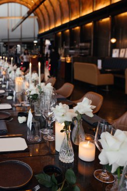 Lüks siyah bir masada sofistike bir kutlama için şık bir masa. Altın şamdanlar, şarap kadehleri, beyaz güller, peçeteler ve bir kağıt isim kartı... İnce bir atmosfer yaratır.. 