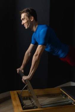 Zayıf erkek balerin pilates ekipmanlarıyla antrenman yapıyor. Zarif duruş, çekirdek gücü, vücut kontrolü. Yüksek kalite fotoğraf