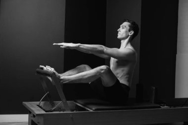 Zayıf erkek balerin pilates ekipmanlarıyla antrenman yapıyor. Zarif duruş, çekirdek gücü, vücut kontrolü. Yüksek kalite fotoğraf