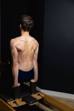Zayıf erkek balerin pilates ekipmanlarıyla antrenman yapıyor. Zarif duruş, çekirdek gücü, vücut kontrolü. Yüksek kalite fotoğraf
