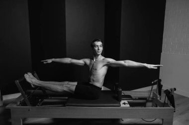 Zayıf erkek balerin pilates ekipmanlarıyla antrenman yapıyor. Zarif duruş, çekirdek gücü, vücut kontrolü. Yüksek kalite fotoğraf