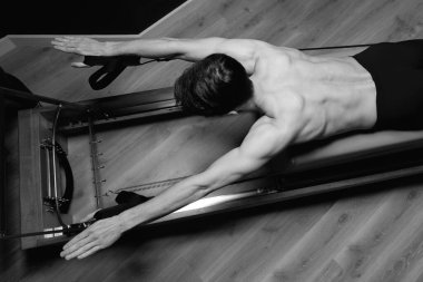Zayıf erkek balerin pilates ekipmanlarıyla antrenman yapıyor. Zarif duruş, çekirdek gücü, vücut kontrolü. Yüksek kalite fotoğraf