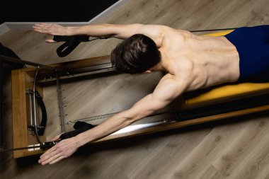 Zayıf erkek balerin pilates ekipmanlarıyla antrenman yapıyor. Zarif duruş, çekirdek gücü, vücut kontrolü. Yüksek kalite fotoğraf