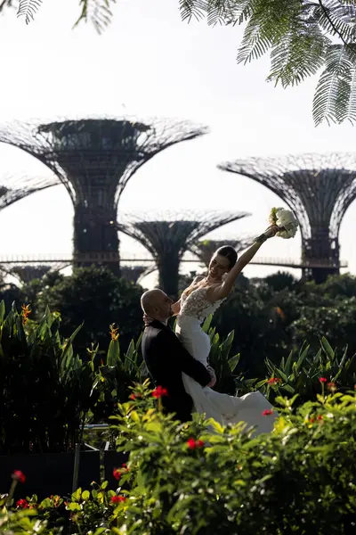 Güzel bir düğün çifti arka plan olarak Singapur Körfezi 'nde Gardens' ı öpüyor. Damat ve gelin Marina Körfezi 'nden Singapur' un bahçesine giden köprüdeler. Yüksek kalite fotoğraf