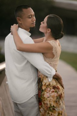 Irklar arası aşk yaşayan bir çiftin romantik yakın çekimi. Koyu tenli Asyalı adam ve zarif elbiseli Avrupalı esmer kadın. Aşk ve birlik, sonsuza dek birlikte. Yüksek kalite fotoğraf