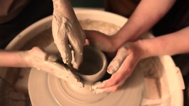 Zanaatkar bir stüdyoda çömlek çarkında çamurla çalışan ellerin yakın çekimi. Yaratıcı hobi, aktif seramik sanat ve özenli el işçiliği. Yüksek kalite 4k görüntü