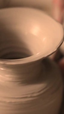 Zanaatkar bir stüdyoda çömlek çarkında çamurla çalışan ellerin yakın çekimi. Yaratıcı hobi, aktif seramik sanat ve özenli el işçiliği. Yüksek kalite 4k görüntü
