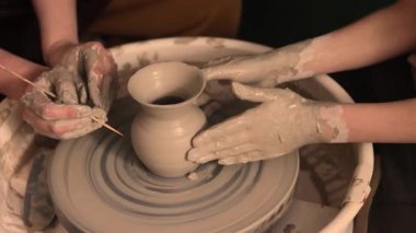 Zanaatkar bir stüdyoda çömlek çarkında çamurla çalışan ellerin yakın çekimi. Yaratıcı hobi, aktif seramik sanat ve özenli el işçiliği. Yüksek kalite 4k görüntü