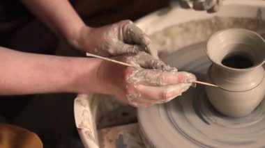 Zanaatkar bir stüdyoda çömlek çarkında çamurla çalışan ellerin yakın çekimi. Yaratıcı hobi, aktif seramik sanat ve özenli el işçiliği. Yüksek kalite 4k görüntü