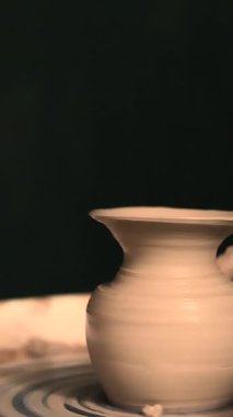 Zanaatkar bir stüdyoda çömlek çarkında çamurla çalışan ellerin yakın çekimi. Yaratıcı hobi, aktif seramik sanat ve özenli el işçiliği. Yüksek kalite 4k görüntü