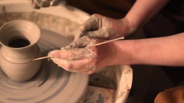 Zanaatkar bir stüdyoda çömlek çarkında çamurla çalışan ellerin yakın çekimi. Yaratıcı hobi, aktif seramik sanat ve özenli el işçiliği. Yüksek kalite 4k görüntü