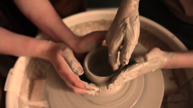 Zanaatkar bir stüdyoda çömlek çarkında çamurla çalışan ellerin yakın çekimi. Yaratıcı hobi, aktif seramik sanat ve özenli el işçiliği. Yüksek kalite 4k görüntü