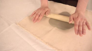  Kadın eli, rahat bir çömlek atölyesinde ahşap bir oklava ile ustaca yuvarlanan kil. Dokunsal yaratıcılığa ve yavaş el yapımı süreçlere odaklan. Yüksek kalite 4k görüntü