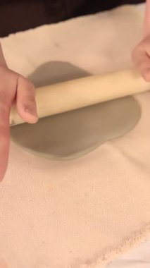  Kadın eli, rahat bir çömlek atölyesinde ahşap bir oklava ile ustaca yuvarlanan kil. Dokunsal yaratıcılığa ve yavaş el yapımı süreçlere odaklan. Yüksek kalite 4k görüntü