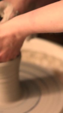 Zanaatkar bir stüdyoda çömlek çarkında çamurla çalışan ellerin yakın çekimi. Yaratıcı hobi, aktif seramik sanat ve özenli el işçiliği. Yüksek kalite 4k görüntü