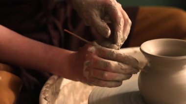 Zanaatkar bir stüdyoda çömlek çarkında çamurla çalışan ellerin yakın çekimi. Yaratıcı hobi, aktif seramik sanat ve özenli el işçiliği. Yüksek kalite 4k görüntü