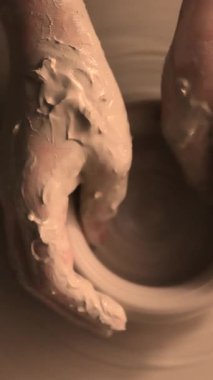 Zanaatkar bir stüdyoda çömlek çarkında çamurla çalışan ellerin yakın çekimi. Yaratıcı hobi, aktif seramik sanat ve özenli el işçiliği. Yüksek kalite 4k görüntü